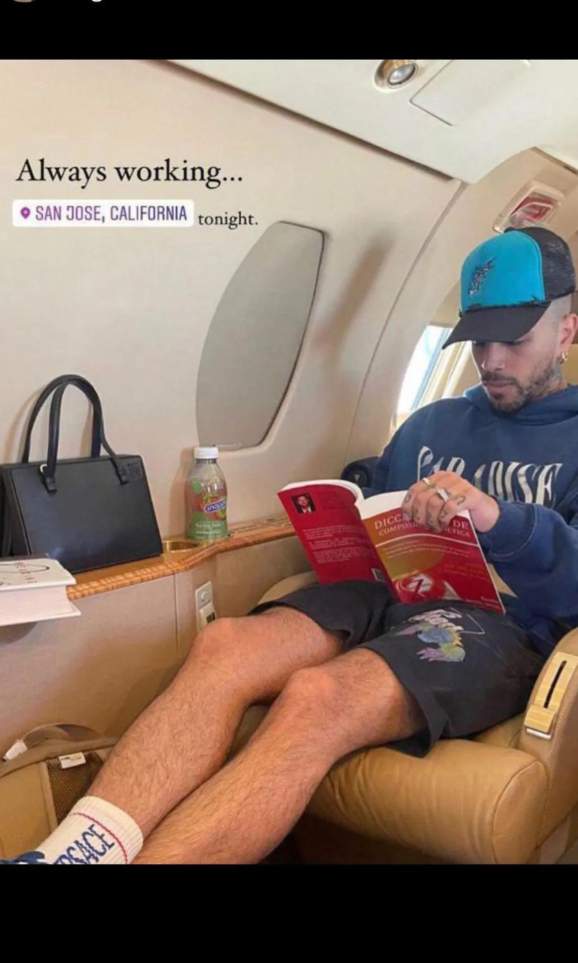Rauw Alejandro sentado en un jet privado leyendo el libro mencionado